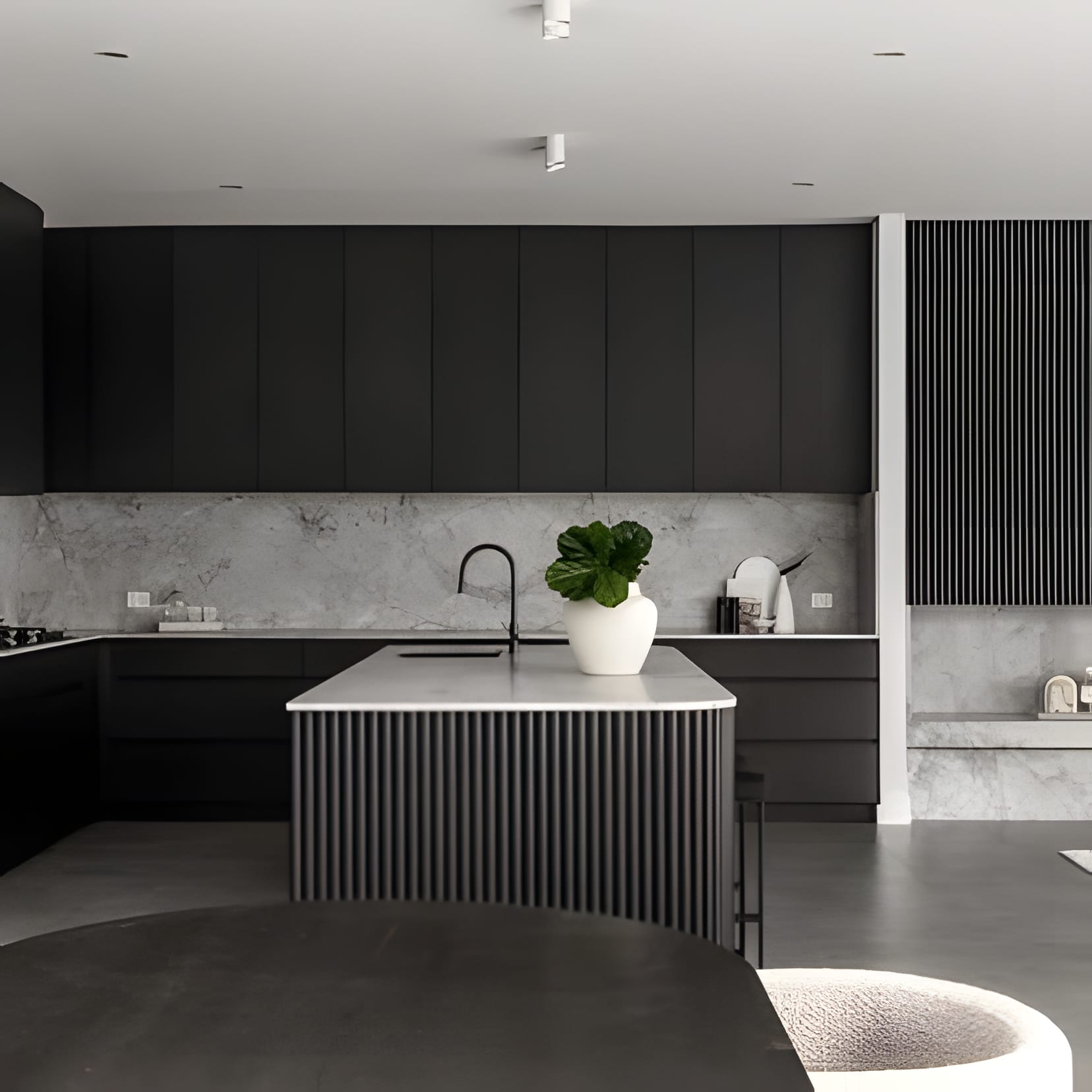 Matte black cabinetry with a fluted island base and a crisp white counter — high contrast, kept simple.