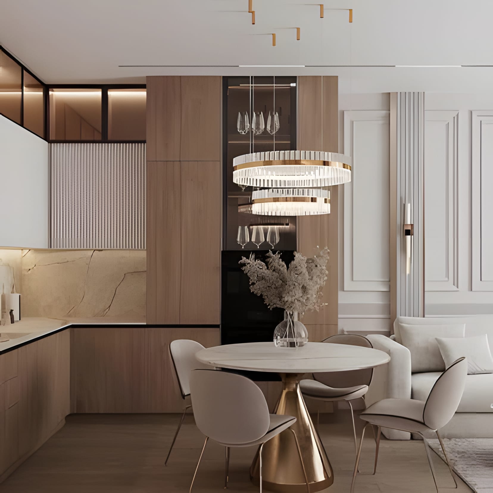 A cream kitchen that reads like a sitting room: walnut tall units, a round dining table, and a ring chandelier.
