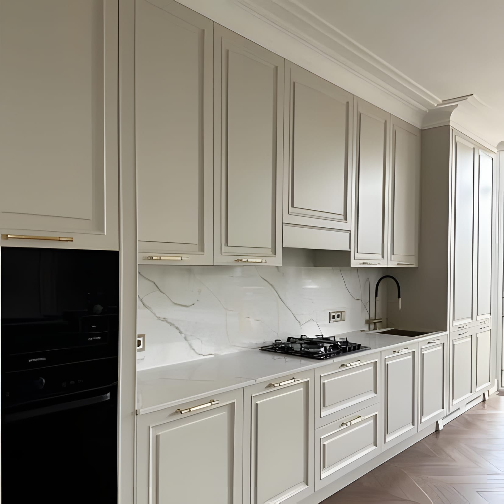 A panelled cream cabinet wall with marble backsplash and a black glass fridge set flush into the run.