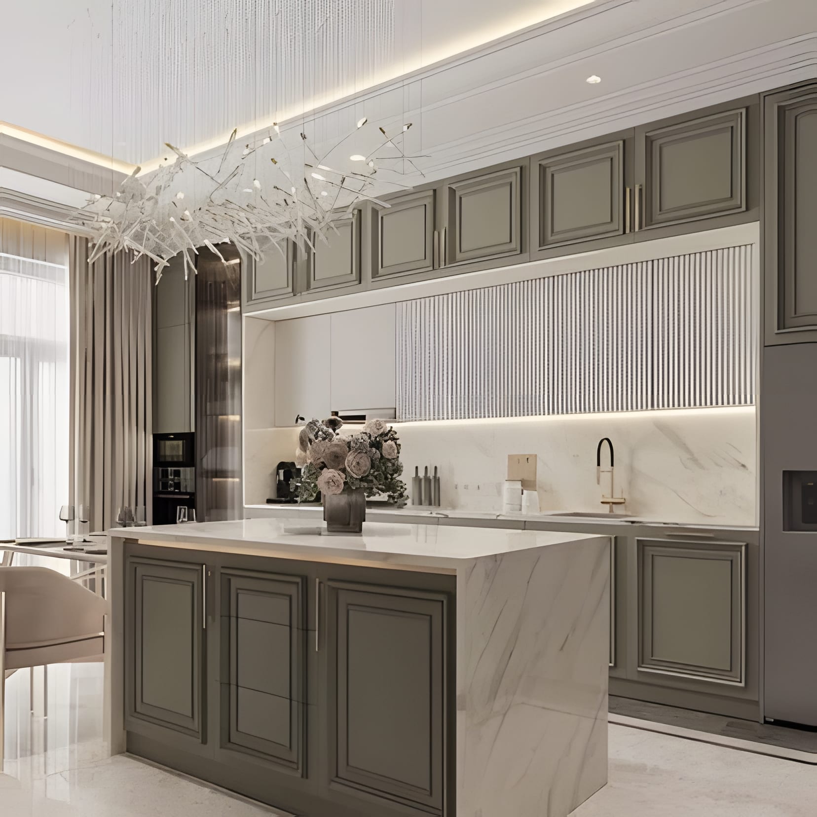 A sage-green classic kitchen with a white fluted feature wall, marble island, and a crystal branch chandelier.