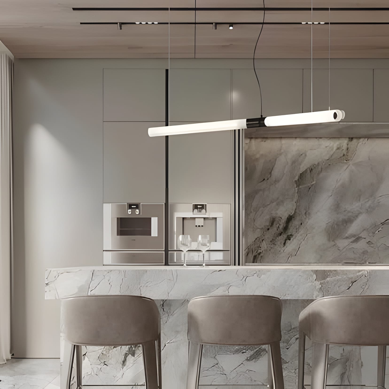 A grey marble wall and island with plush velvet stools under a tube pendant.
