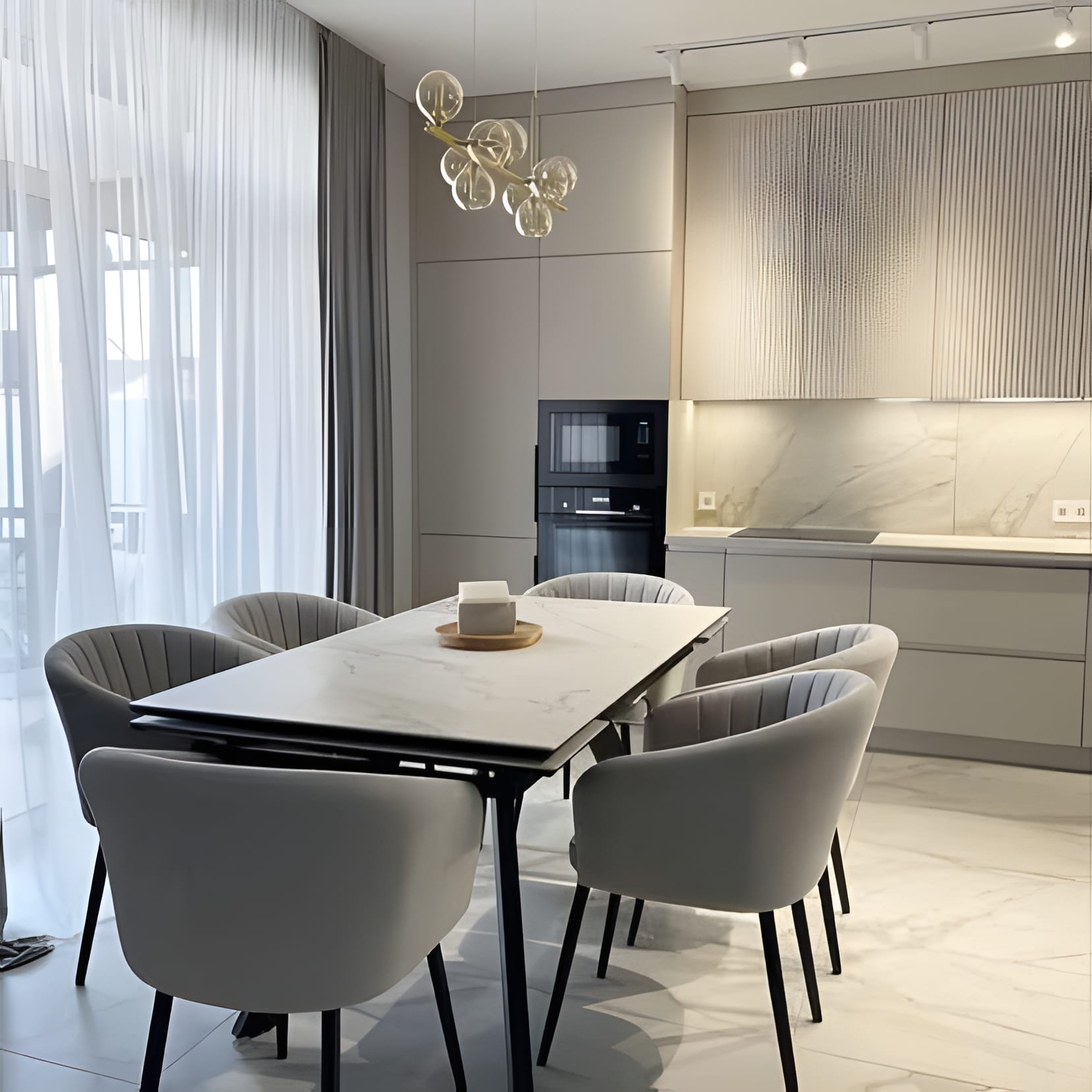 A grey dining room off the kitchen with hexagon mirrors and soft grey chairs around a dark table.
